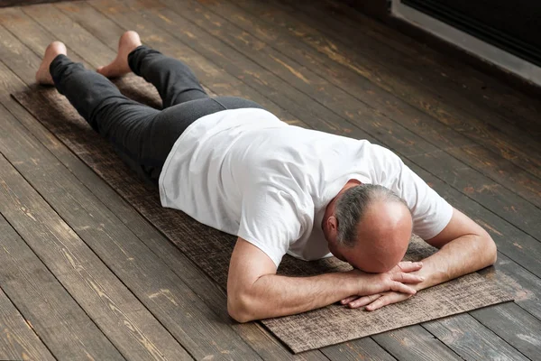 Starszy człowiek w wieku odpoczynku po ćwiczeniami jogi na podłodze. Sport w domu dla zdrowia. — Zdjęcie stockowe