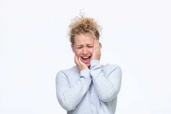 Блондинка в голубом свитере с ужасной головной болью — стоковое фото