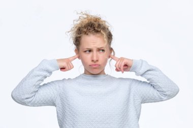 hoşnutsuzluk olan sarışın kız gürültü ile rahatsız olan kulakları tıkanan bakmak