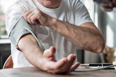 Adam onun hayati istatistikleri kontrol etmek için ev tansiyon makinesi kullanarak.