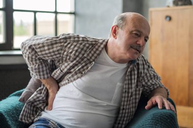 Üst düzey adam sırtında ani ağrı hissi koltuk üzerinde kapalı oturan