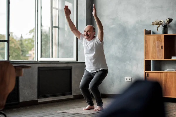 Sandalye poz veya Utkatasana yapıyor oturma odasında kapalı yoga Adam — Stok fotoğraf