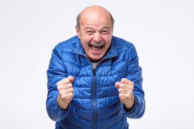 Şanslı başarılı yaşlı adam bağırıyor, yumruksıkma, kazanan bir görünüme sahip