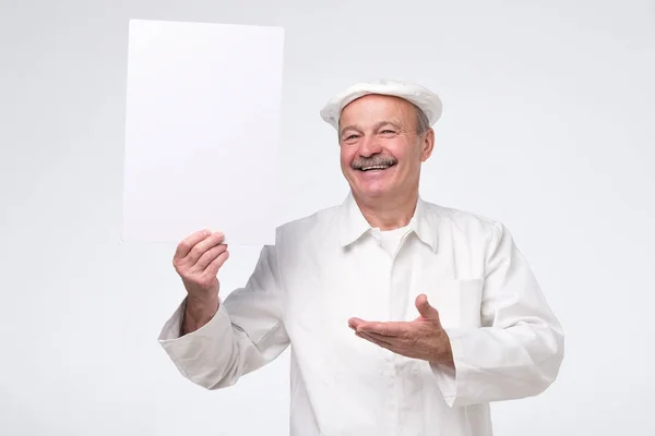 Spanisch reifen Koch hält Kopierraum auf Palme, Blick in die Kamera lächelnd, — Stockfoto