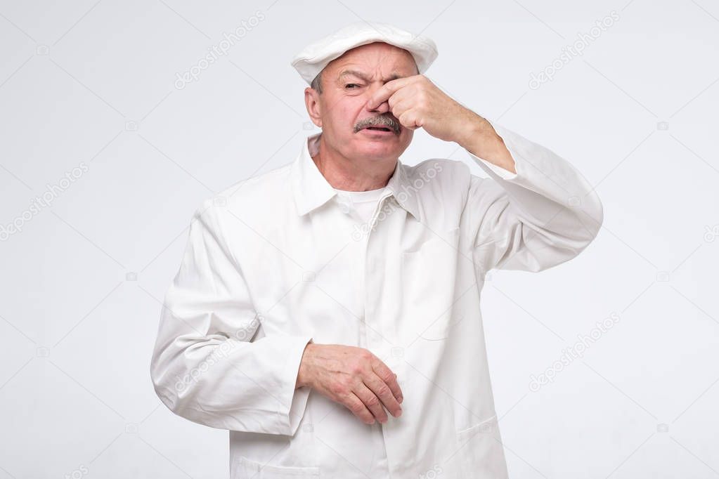Chef cook covering nose because of disgusting odor.