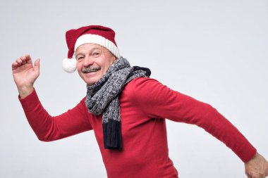 Kırmızı noel şapkalı İspanyol olgun adam hızlı koşuyor. Yan görünüm.