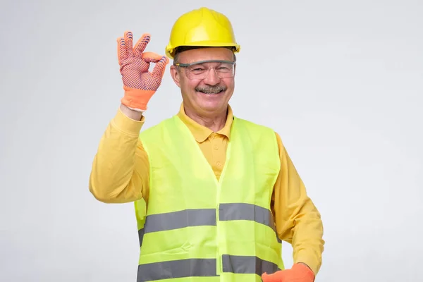 Trabajador de construcción hispano mayor con sombrero duro mostrando una señal aceptable — Foto de Stock