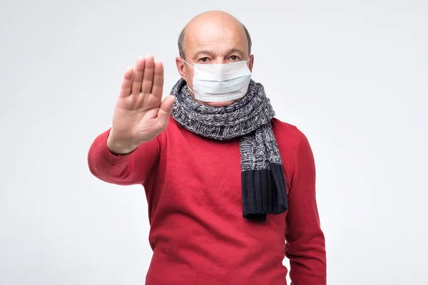 Senior in medizinischer Maske zeigt Gestenstopp — Stockfoto