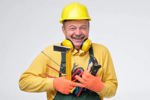 Sonriente plomero hispano mayor sosteniendo herramientas en las manos . — Foto de Stock