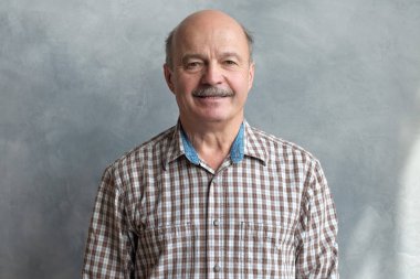 gri duvar üzerinde gülümseme ile sakin olgun kel İspanyol erkek.