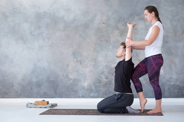 Yoga eğitmeni kaslarını germek için onu öğrenci yardım. — Stok fotoğraf