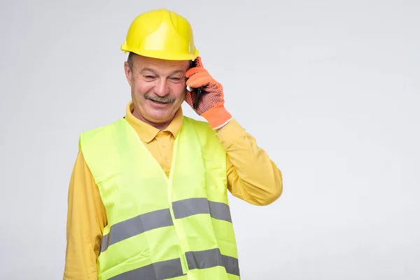 Reparador en casco protector hablando en su teléfono con el cliente — Foto de Stock