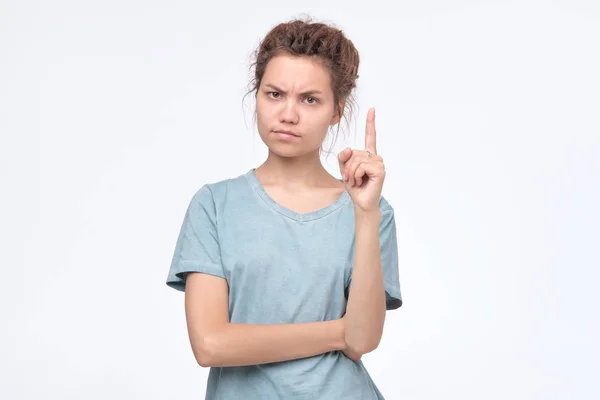 Serious strict young woman looks stressed and pointing up with finger — Stock Photo, Image