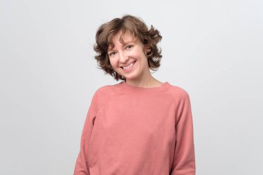 Kırmızı kazaklı güzel, dost canlısı bir kadın kameraya bakıyor..