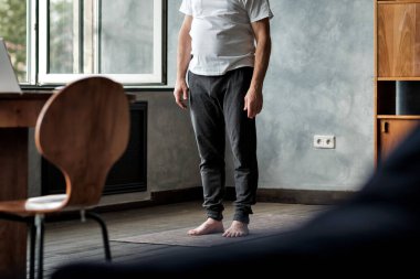 Üst düzey İspanyol antrenman yapıyor, yoga minderinin üstünde duruyor.