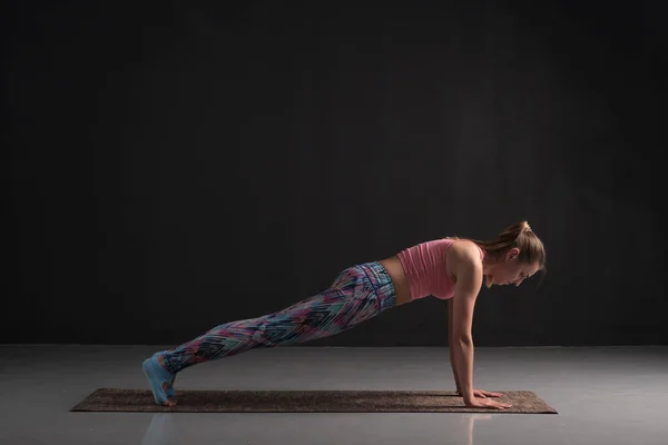 Mujer practicando yoga, haciendo ejercicios de flexiones, phalankasana, pose de tablón . — Foto de Stock