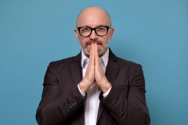 Takım elbiseli ve gözlüklü yalvaran bir adam el ele dua ediyor..