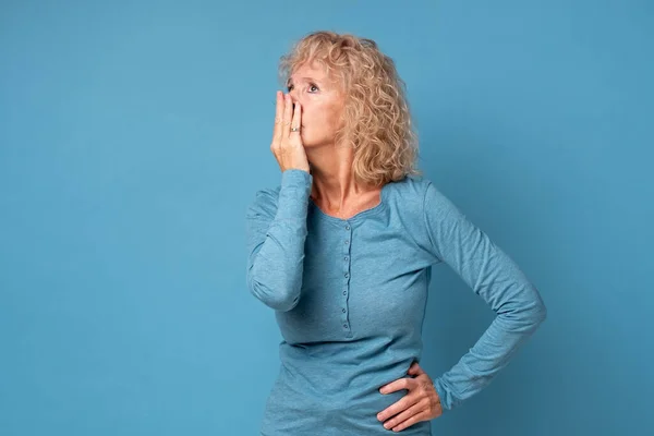 Налякана старша жінка середнього віку, що покриває рот руками, відчуває себе жахливо — стокове фото