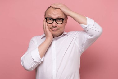 Olgun yakışıklı bir adam. Yüzünde aptal bir ifade ve komik bir bakış var.