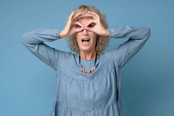Mujer bastante caucásica sosteniendo los dedos cerca de los ojos como gafas —  Fotos de Stock