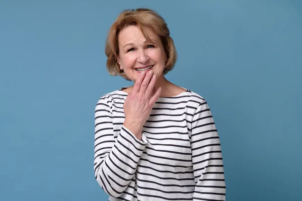 Mature caucasian woman laughing covering mouth with hand. — Stock Photo, Image