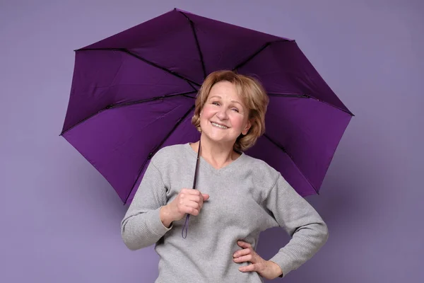 Senior caucasian smiling woman with umbrella ready for rain