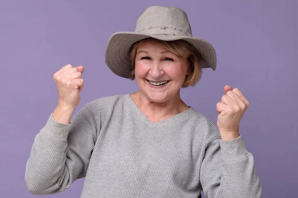 Feliz anciano caucásico mujer en verano sombrero bombeo puños hasta, celebrar el éxito — Foto de Stock