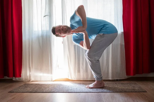 Caucasian man in twisted Chair pose at home — Stock Photo, Image