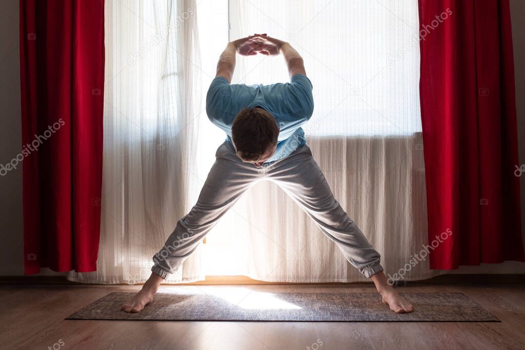 man working out standing in asana Wide Legged Forward Bend
