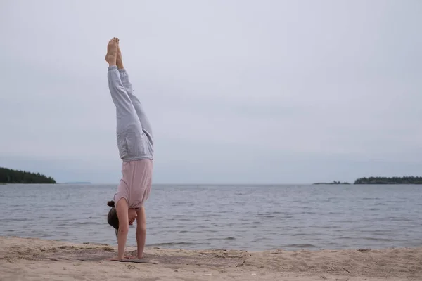 Woman practicing yoga doing handstand on beach outdoor. — Stock Photo, Image