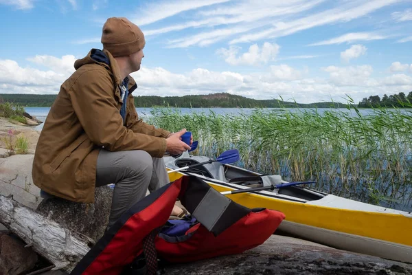 Mann sitzt am Ufer und ruht sich nach aktivem Paddeln aus — Stockfoto