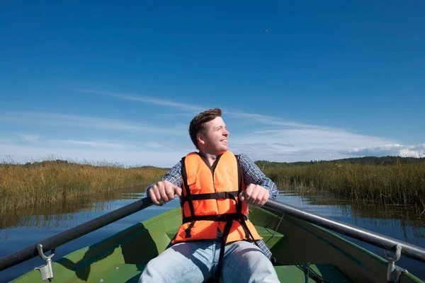 Ein junger Mann in Schwimmweste sitzt in einem Boot — Stockfoto