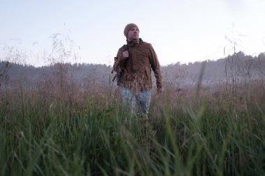 Akşam sisli bir çayırda yürüyen bir adam..