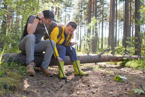 Junge Frau und Mann ruhen auf umgestürztem Baum und haben Schmerzen im Knie. — Stockfoto