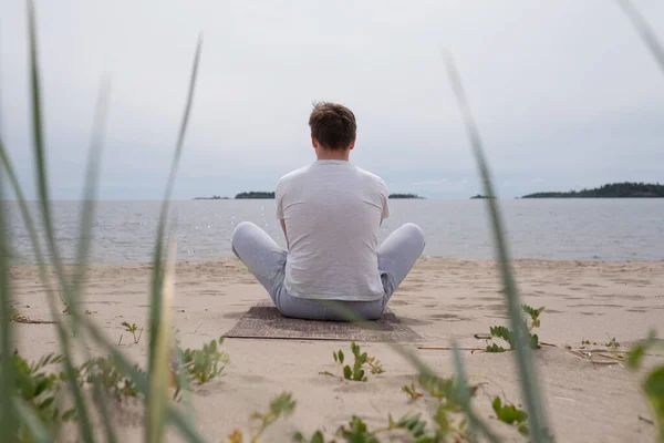 Młody człowiek medytujący nad morzem. Widok z tyłu — Zdjęcie stockowe