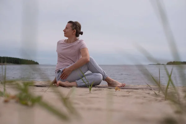 Женщина практикует йогу на песчаном пляже . — стоковое фото