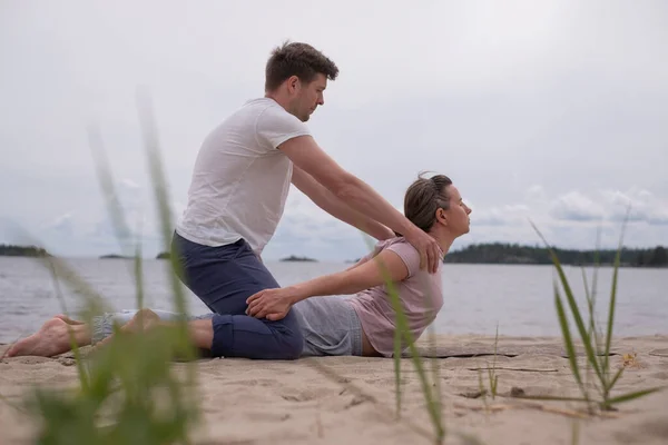 Hombre ayudando a la mujer a hacer yoga bhujangasana cobra pose — Foto de Stock