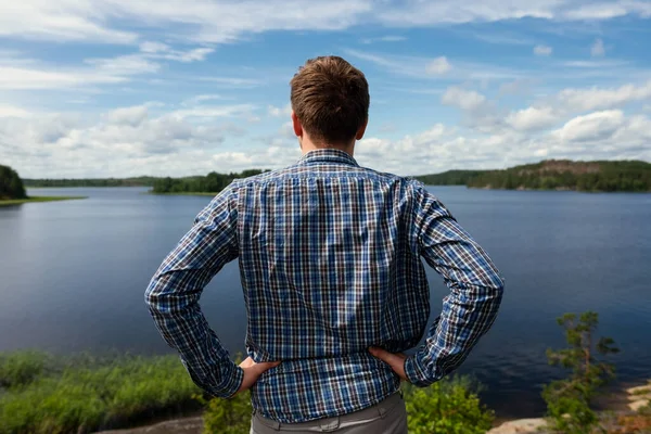 Widok z tyłu człowieka patrząc jezioro odpoczynku podczas trekkingu. — Zdjęcie stockowe