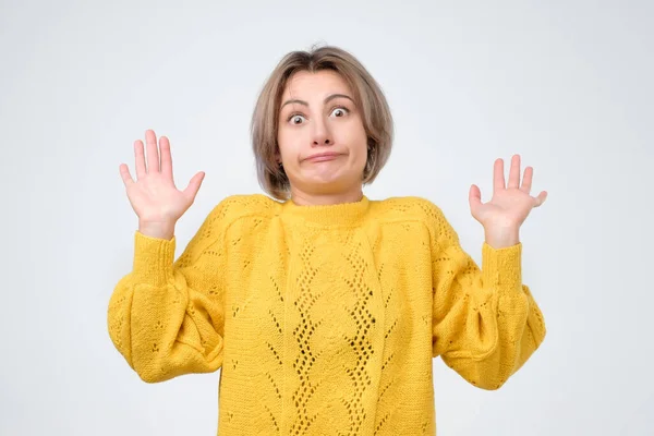 Woman in yellow sweater, raising palm in surrender and smirking at camera — Stock Photo, Image