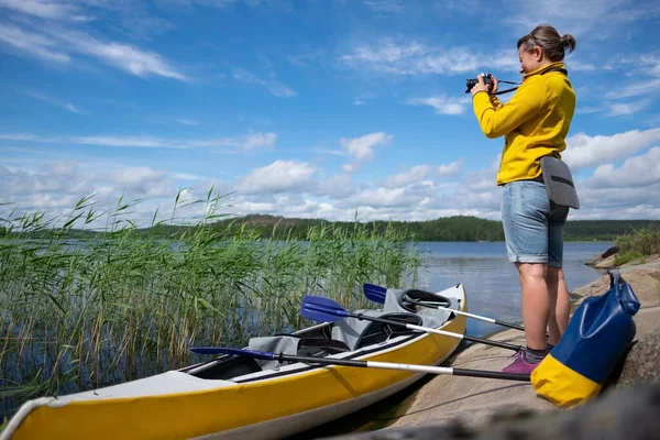 Frau ruht sich nach Kajakfahren am See aus und macht Fotos mit der Kamera. — Stockfoto