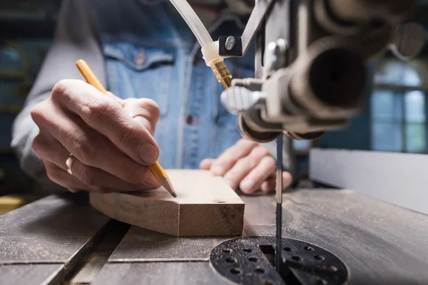 Vista de un carpintero usando un lápiz para dibujar una línea en una tabla de madera. — Foto de Stock