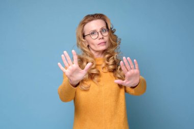 Stresli, sinirli, olgun bir kadın. El hareketlerini durduruyor.