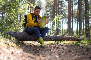 Bir patikada oturan kadın yürüyüşçünün çizmeleriyle sorunları var..
