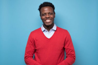 Afrikalı gülümseyen genç bir adamın portresi. Stüdyo resmi mavi duvarda.