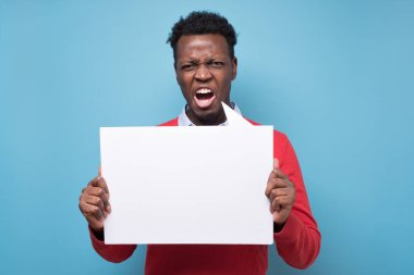 Elinde boş pankartlar tutan Afrikalı genç adam mavi arka planda hakları için savaşıyor. Eylemcilik, aktif vatandaşlık, sosyal yaşam, protesto, insan hakları kavramı.