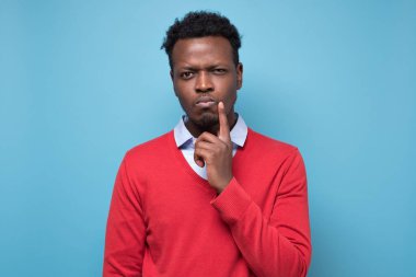 Yakışıklı Afrikalı bir adam plan yapmayı düşünüyor. Stüdyo resmi mavi duvarda.