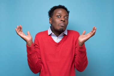 Afro-Amerikalı genç adam işaret dilini bilmiyor ve kafası karışık. Mavi arkaplanda izole