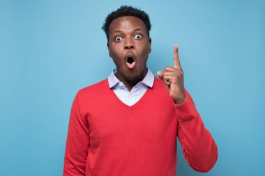 Şaşırmış Afrikalı bir adam işaret ederek tavsiye veriyor. Stüdyo resmi mavi duvarda.