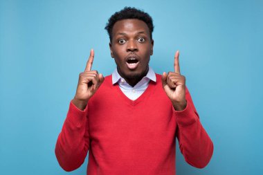 Şaşırmış Afrikalı bir adam işaret ederek tavsiye veriyor. Stüdyo resmi mavi duvarda.