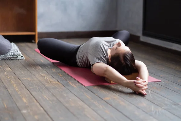 Woman practicing yoga in Reclined Butterfly exercise, supta baddha konasana — Stock Photo, Image